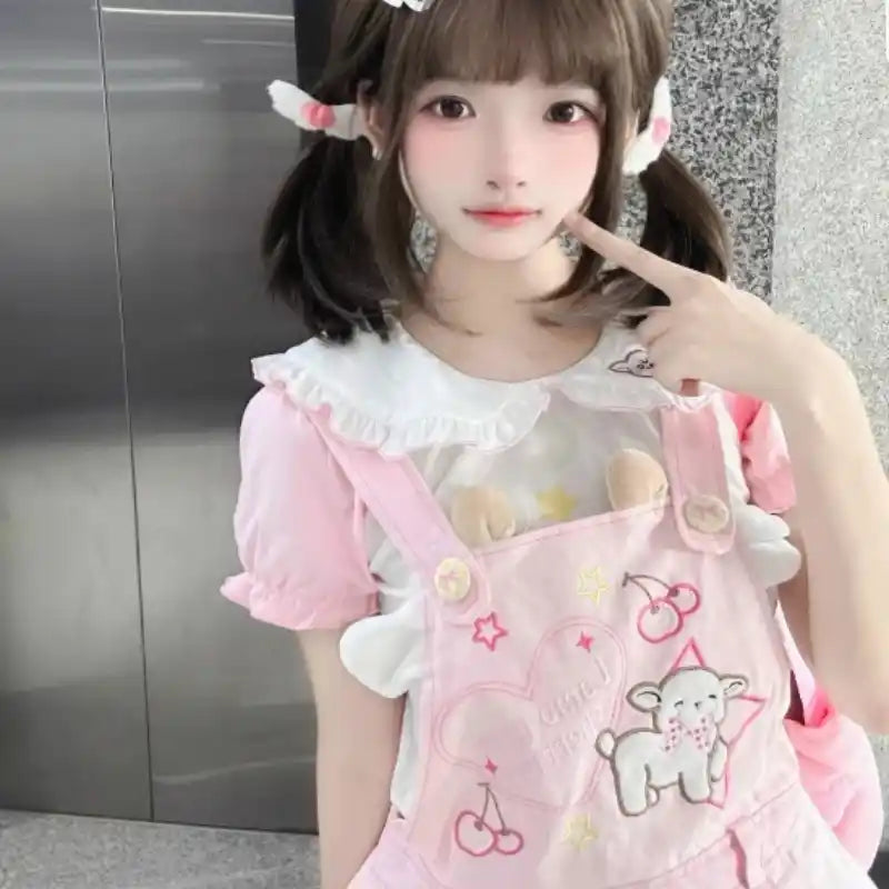 Flat lay of pastel pink suspender skirt and matching tee set with softcore kawaii aesthetic