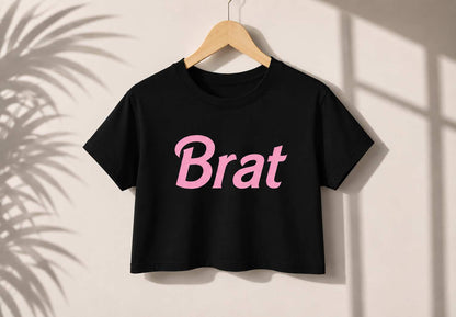 Flat lay of DDLGirl Brat Energy Crop Top showing pink Brat graphic and white crop design for DDLG ABDL kawaii cutecore bratcore gifting
