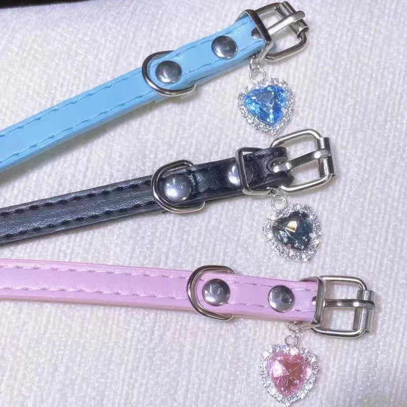 Set of three vegan leather chokers in blue, black, and pink with heart pendants and adjustable straps