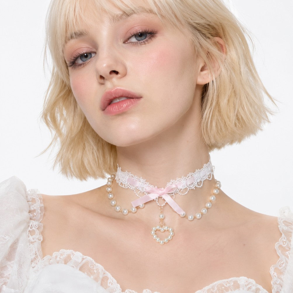 Close up of open heart pendant with pearl detailing on pink coquette lace choker
