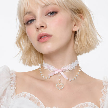 Close up of open heart pendant with pearl detailing on pink coquette lace choker