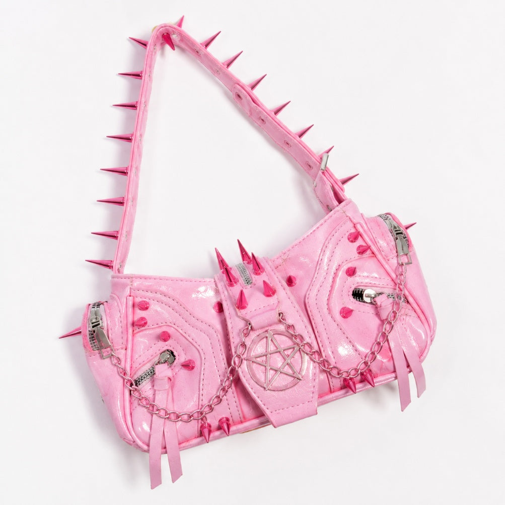 Flatlay of pink kawaii punk shoulder bag styled with gothic and DDLG accessories